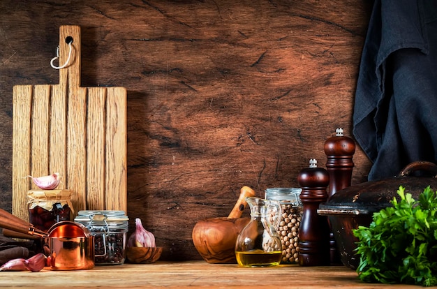 Cooking background Rustic wooden kitchen table cast iron pan spice grinders cutting board spices and seasonings storage jars Copy space