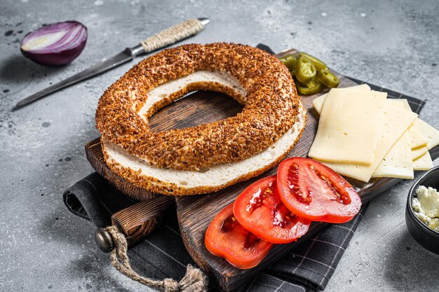 Cooking Bagels Sandwiches with cream cheese, ham, tomato and green rocket. Gray background. Top view.