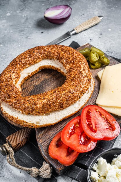 Cooking Bagels Sandwiches with cream cheese, ham, tomato and green rocket. Gray background. Top view.