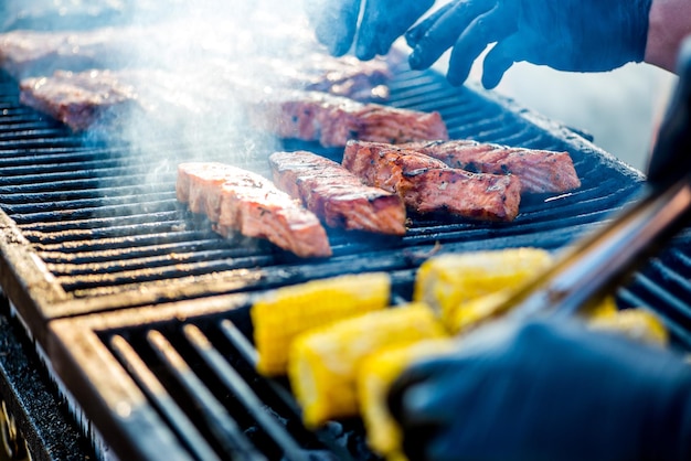 BBQ 魚の調理手袋をはめた手がグリルで魚を回転させます