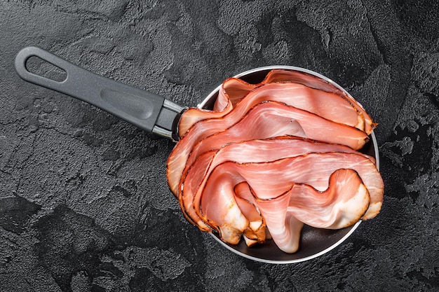 Photo cooking of black forest ham in skillet. black background. top view.