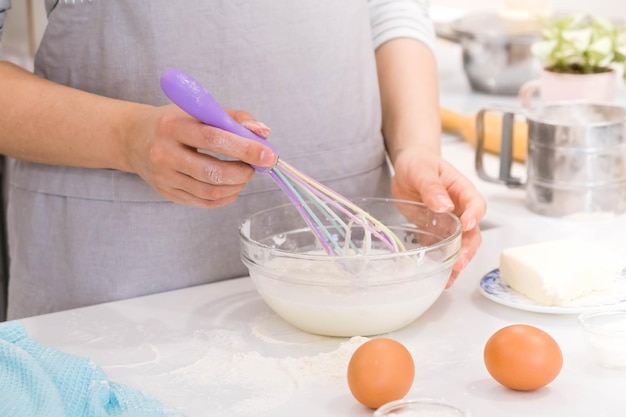 Cooking blogger is cooking at the kitchen in sunny day and is making photo at smartphone of cooking process Young pretty woman cooking at kitchen