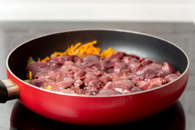 Cooking chicken liver in a frying pan closeup with vegetables Selective focus