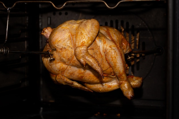 Photo cooking chicken in the oven or in a rotisserie machine on a grill spit. home cooking.