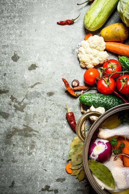 Cooking chicken soup with vegetables in a large poton stone table.