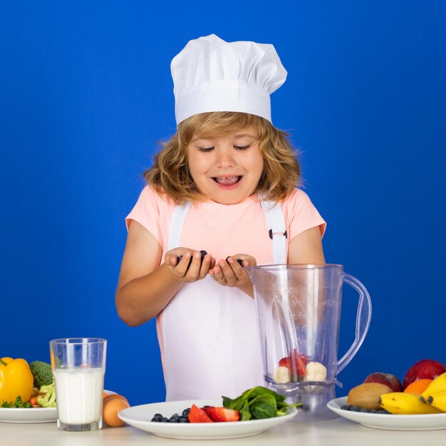 Cooking children chef kid boy making fresh vegetables for healthy eat portrait of little child in fo