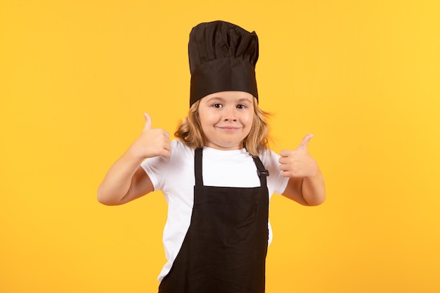 Cooking children Chef kid boy making healthy food Portrait of little child in chef hat isolated on studio background Kid chef Cooking process