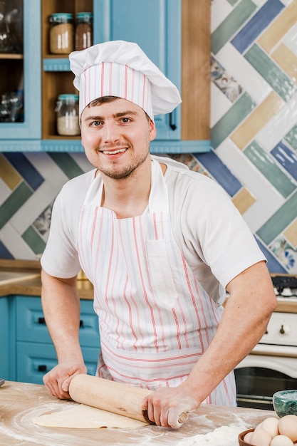 Cooking concept Happy male chef holding a rolling pin for dough