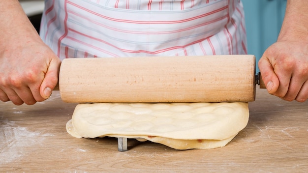 Cooking concept Happy male chef holding a rolling pin for dough