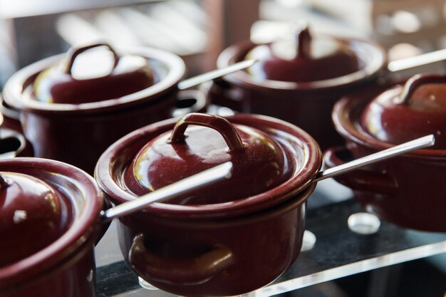 Cooking, culinary, eating and asian kitchen concept - close up of hot food pots at restaurant