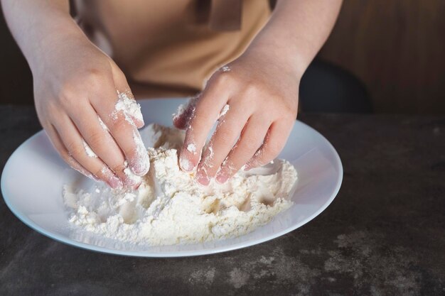 Foto scuola di cucina o di cucina per bambini bambina con le mani imbrattate di farina che si diverte a cucinare in cucina e scherzare