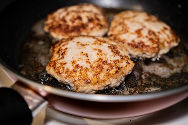 Cooking cutlets in a frying pan on an induction hob White steam is hovering over hot cutlets in a frying pan