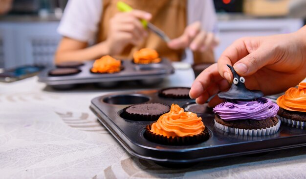 맛있는 수제 케이크를 요리하고 할로윈 축제를 위해 컵케이크를 장식하세요. 집에서 부엌에서 달콤한 음식 디저트를 위한 재료를 준비하고 섞습니다.