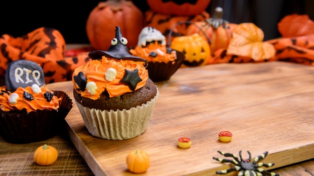 Cucinare una deliziosa torta fatta in casa e decorare cupcake per le feste di halloween. dessert dolce e decorazione per la festa a casa.