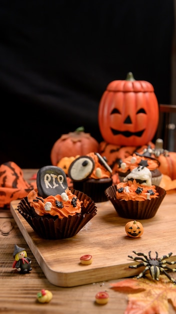 Cucinare una deliziosa torta fatta in casa e decorare cupcake per le feste di halloween. dessert dolce e decorazione per la festa a casa.