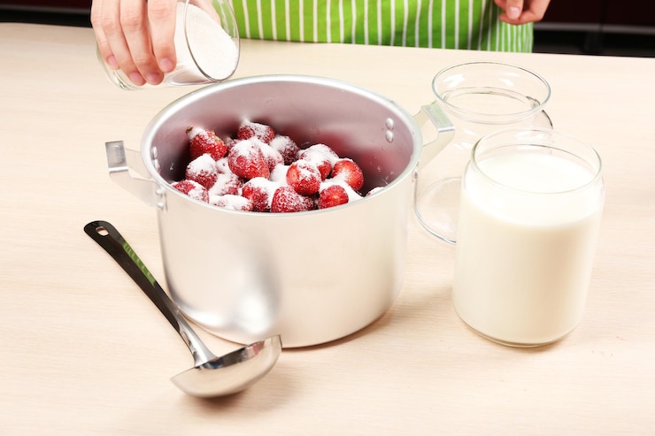 Photo cooking delicious strawberry jam in kitchen