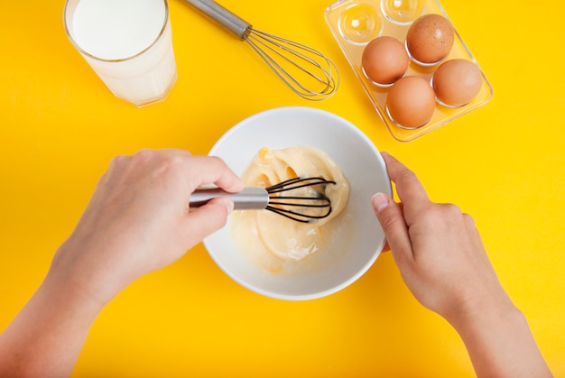 Cooking dessert or breakfast. Hands mixing raw eggs in bowl.