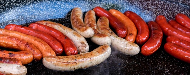 Photo cooking different types of sausages on the grill delicious sausages closeup banner