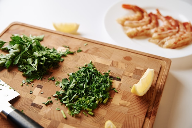 Cooking dinner. Chopped parsley on a cutting board and fresh shrimp on the table