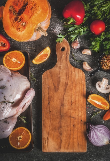 Cooking dinner for christmas, Thanksgiving. Traditional autumn ingredients are vegetables, pumpkin, mushrooms, chicken or turkey, fresh herbs, spices.  dark table, Top view 