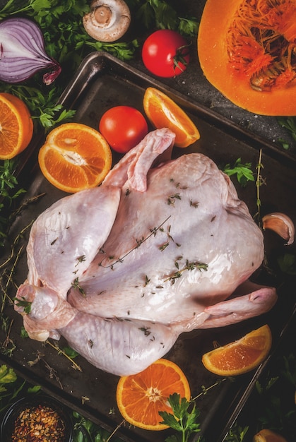 Cooking dinner for christmas, Thanksgiving. Traditional autumn ingredients are vegetables, pumpkin, mushrooms, chicken or turkey, fresh herbs, spices. On a dark table, Top view