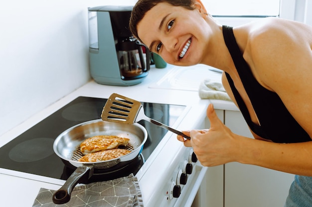 cooking dinner at home with positive emotions, young woman chef shows quality of food and offers to