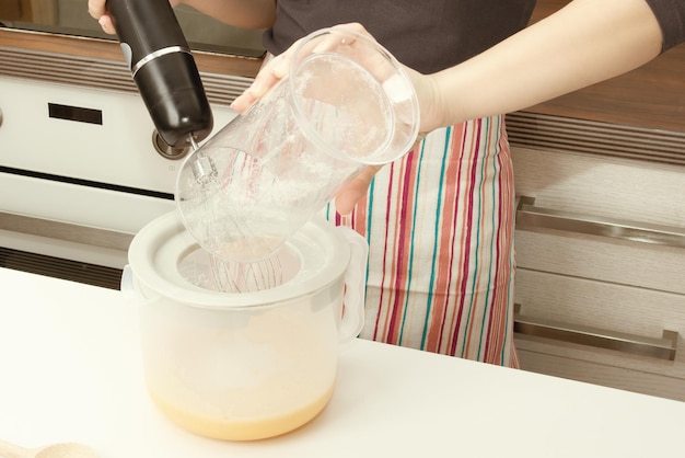 Cooking dough. Girl beats with a mixer chicken eggs with sugar in a bowl in the kitchen.