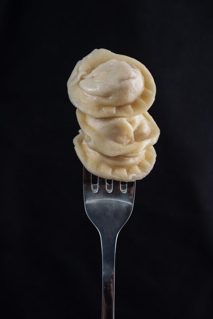 Cooking dumplings on a fork on a black background