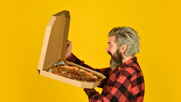 Cooking food concept giving food order and holding pizza hungry man eating pizza fast food delivery eating delicious cheesy pizza happy bearded man italian food italy is here