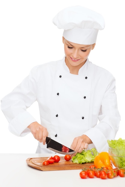 cooking and food concept - smiling female chef, cook or baker chopping vegetables