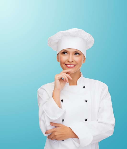 cooking and food concept - smiling female chef, cook or baker dreaming