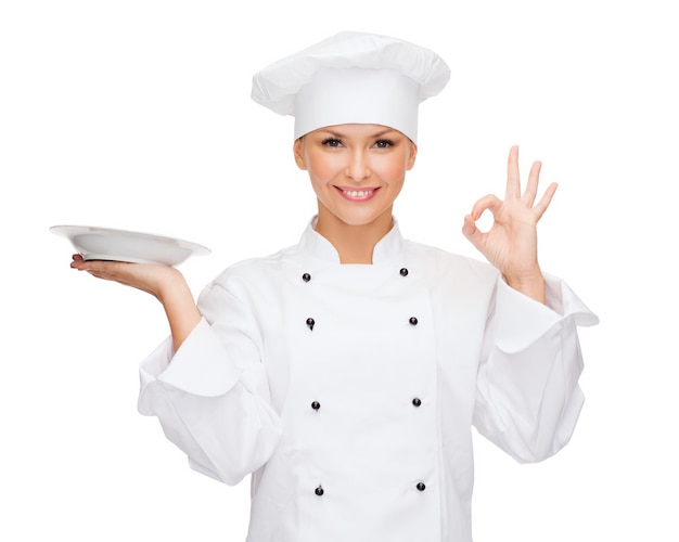 cooking and food concept - smiling female chef, cook or baker with empty plate showing ok sign