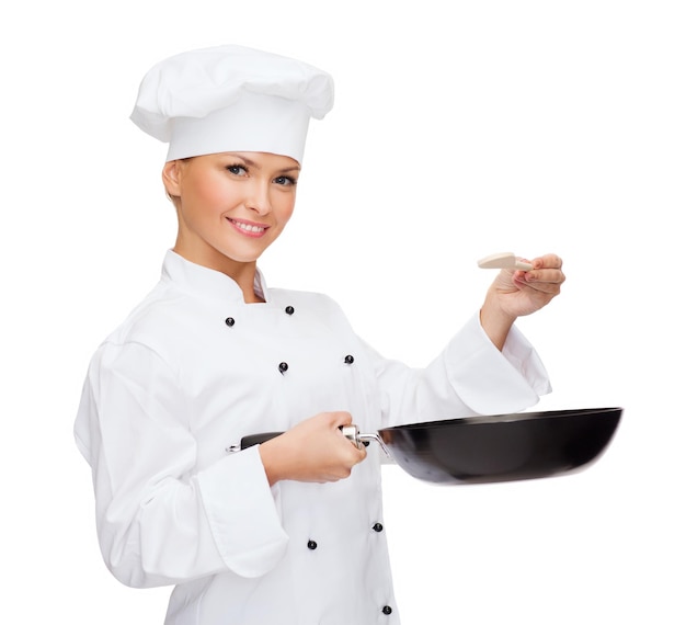 Concetto di cucina e cibo - chef, cuoca o fornaio sorridente con padella e cucchiaio da degustazione