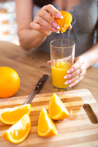 Cooking food and concept of veganism vigor and healthy eating  close up of female hand squeeze fresh orange juice