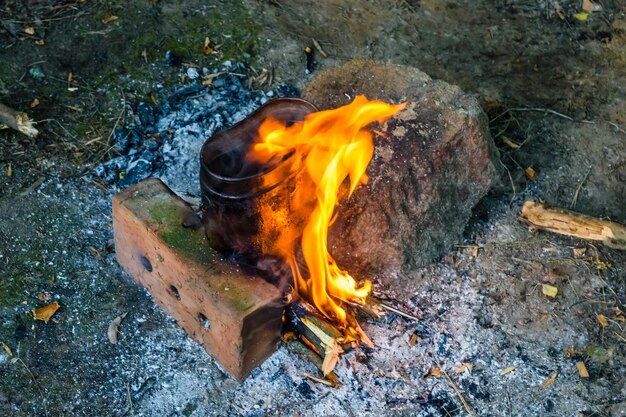 Cooking food in a kettle on bonfire in forest