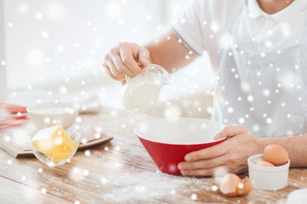 料理、食べ物、人、家のコンセプト-ボウルにミルクを注ぐ男のクローズアップ