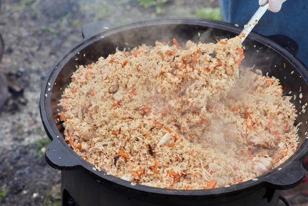 Cooking food or pilaf in a cauldron on fire Cooking in cauldron on open fire in nature Bowler on bonfire in forest Closeup fire flame