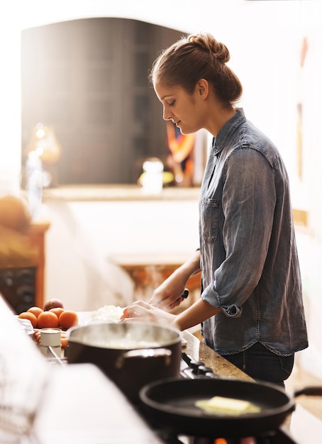 Photo cooking food and woman with a pan in the kitchen for lunch dinner or supper in a modern house diet wellness and female chef preparing a healthy meal recipe in a pot on a stove at her home