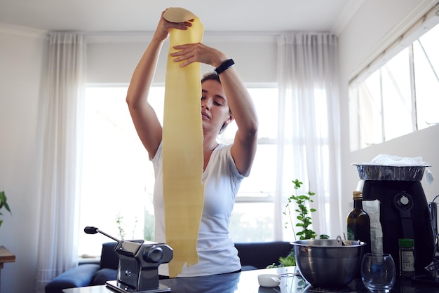 ゼロから調理する自宅で自家製パスタを調理する魅力的な若い女性のトリミングされたショット