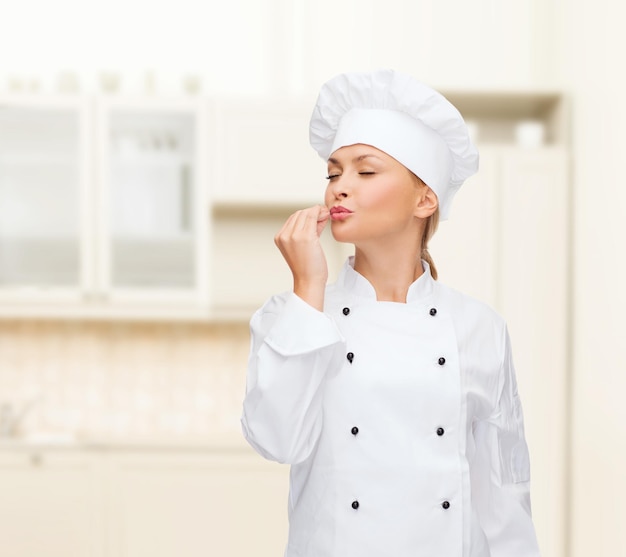 cooking, gesture and food concept - smiling female chef showing delicious gesture