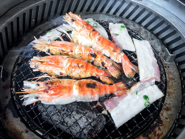 철판에 구운 오븐 숯불 그릴로 구운 새우 요리. 아래는 매우 뜨거운 숯입니다.