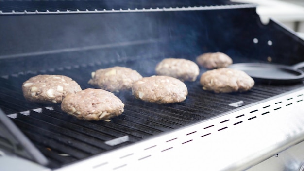 Cooking hamburger beef patties on a gas grill.