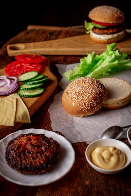 햄버거 또는 치즈 버거 요리 클래식 햄버거를 위한 다른 재료 구운 고기 야채 채소 소스 참깨 롤빵 나무 배경