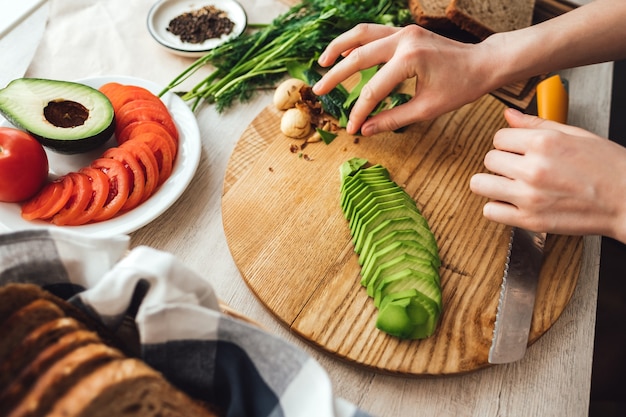 Cooking healthy sandwich with avocado and tomato at home in the kitchen.