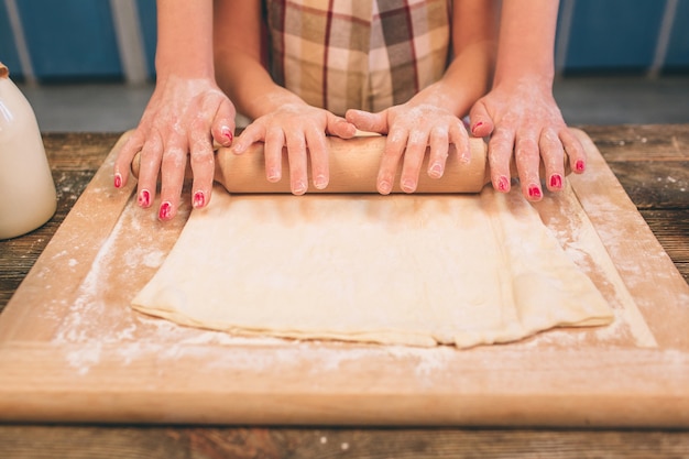 Cooking homemade cakes. Happy loving family are preparing bakery together. Mother and child daughter girl are cooking cookies and having fun in the kitchen. Roll the dough.