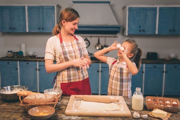 Cooking homemade cakes. Happy loving family are preparing bakery together. Mother and child daughter girl are cooking cookies and having fun in the kitchen. Roll the dough.