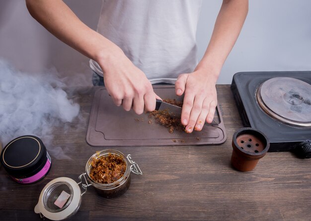 Cucinare il narghilè nel bar. tagliare il tabacco in una ciotola. ristorante, bar con narghilè, bar per fumatori.