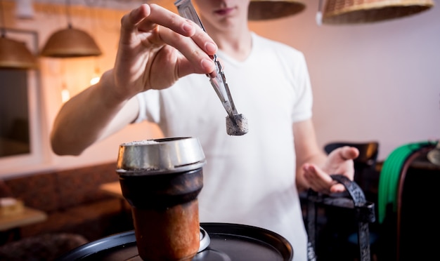 バーで水ギセルを調理します。レストラン、水ギセルバー、喫煙カフェで水ギセルと若い男。