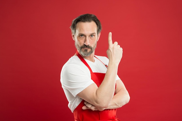 Cooking is passion Man mature cook posing cooking apron Fine recipe Ideas and tips Chief cook and professional culinary Cook food at home Cook with beard and mustache wear apron red background