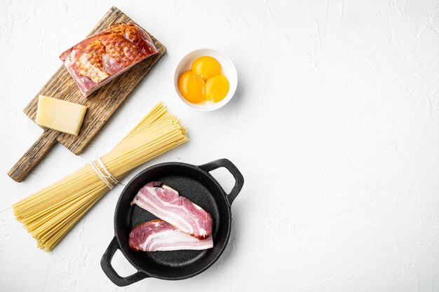 Cooking italian food collage. Ingredients for carbonara pasta, spaghetti, oil, ham, egg and parmesan set, on white stone surface, top view flat lay